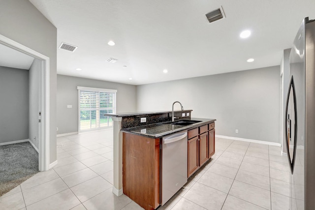 kitchen with sink, an island with sink, stainless steel appliances, and light tile patterned floors