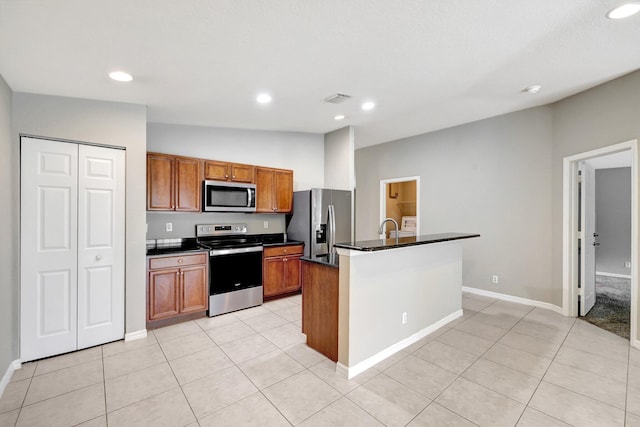 kitchen featuring appliances with stainless steel finishes, sink, lofted ceiling, an island with sink, and light tile patterned flooring