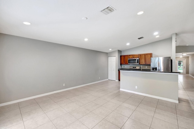 kitchen with lofted ceiling, stainless steel appliances, and light tile patterned floors