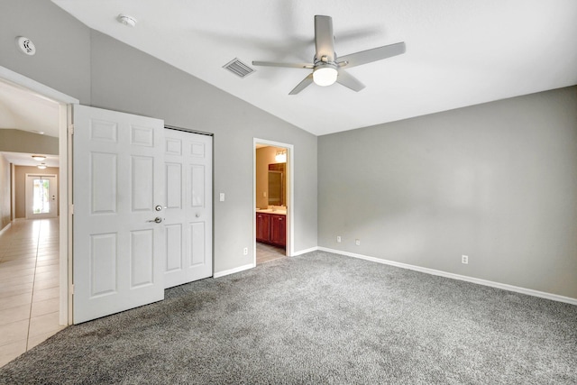 unfurnished bedroom featuring ensuite bathroom, a closet, vaulted ceiling, carpet, and ceiling fan