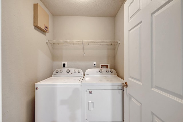 clothes washing area featuring washing machine and dryer and a textured ceiling