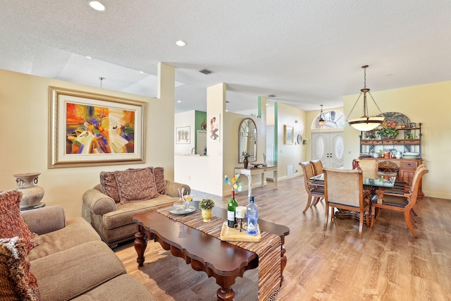 living room with a textured ceiling, light hardwood / wood-style flooring, and vaulted ceiling