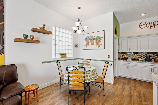 dining room featuring light hardwood / wood-style floors, a textured ceiling, and an inviting chandelier