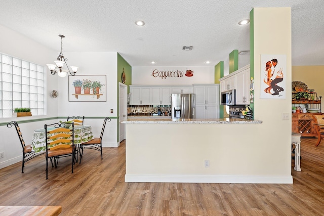 kitchen featuring light hardwood / wood-style flooring, white cabinets, kitchen peninsula, and stainless steel appliances