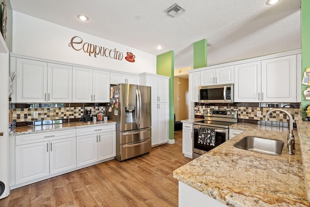 kitchen with sink, white cabinets, tasteful backsplash, and stainless steel appliances