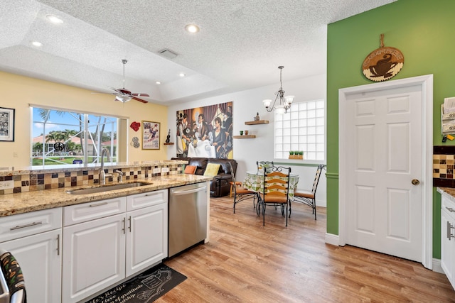 kitchen featuring sink, stainless steel dishwasher, backsplash, and a raised ceiling