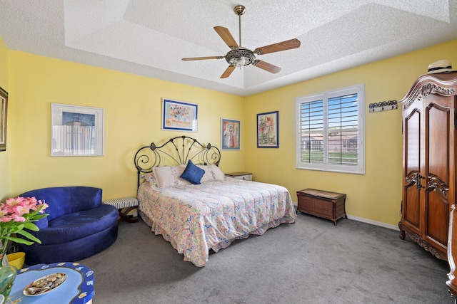 bedroom with carpet flooring, a tray ceiling, a textured ceiling, and ceiling fan