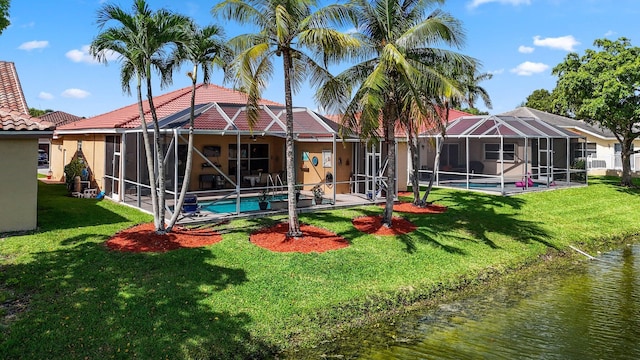 rear view of house featuring a lanai, a lawn, and a water view