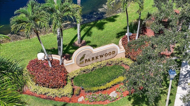 community / neighborhood sign featuring a lawn and a water view