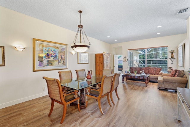 dining room with hardwood / wood-style floors and a textured ceiling