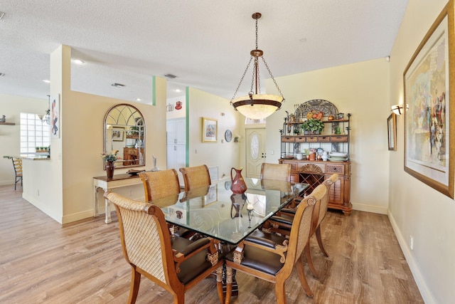 dining area featuring light hardwood / wood-style flooring and a textured ceiling