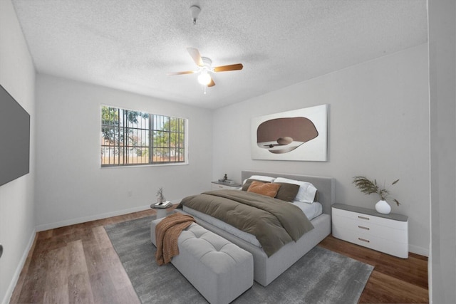 bedroom with a textured ceiling, ceiling fan, wood finished floors, and baseboards