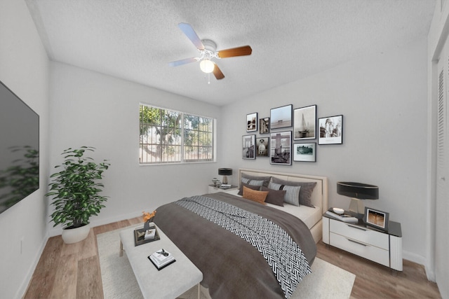 bedroom with hardwood / wood-style floors, a textured ceiling, a closet, and ceiling fan