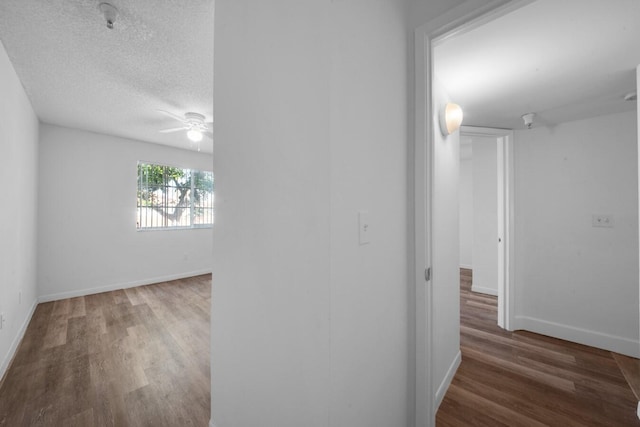 corridor featuring a textured ceiling and hardwood / wood-style floors