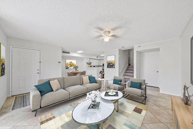 living room with light tile patterned floors, stairs, visible vents, a ceiling fan, and a textured ceiling