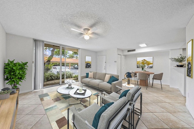 living room featuring light tile patterned flooring, visible vents, a ceiling fan, and a textured ceiling
