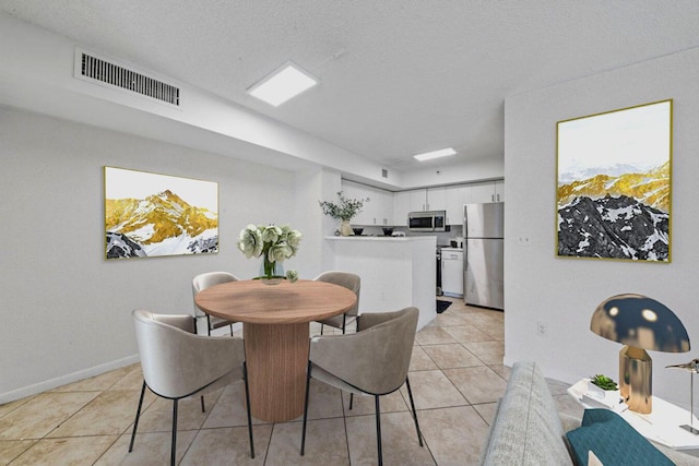 dining space with baseboards, visible vents, light tile patterned floors, and a textured ceiling