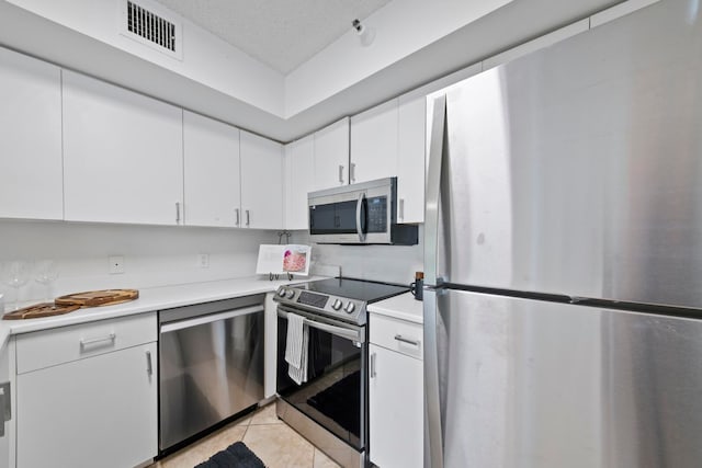 kitchen featuring appliances with stainless steel finishes, light tile patterned floors, and white cabinetry