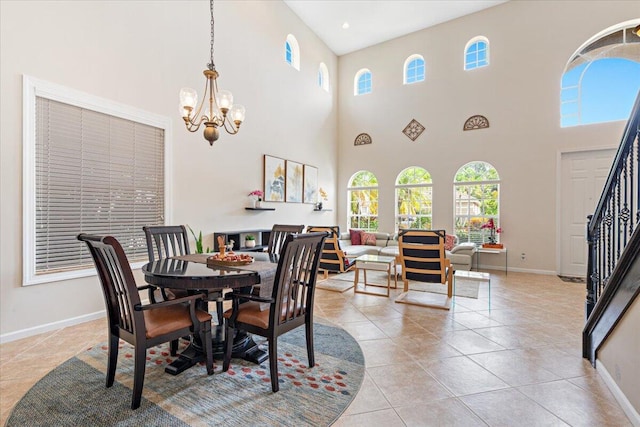 dining area with a towering ceiling, an inviting chandelier, and light tile patterned floors