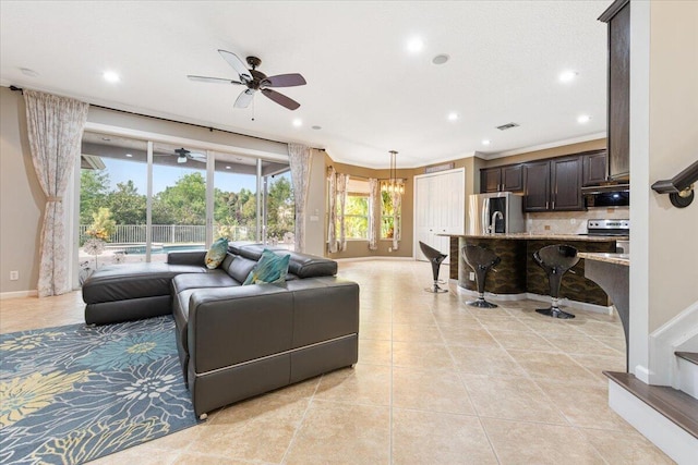 tiled living room with ornamental molding and ceiling fan with notable chandelier