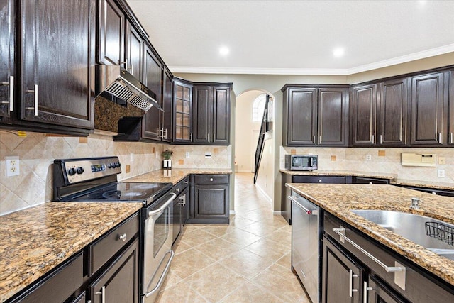 kitchen featuring ornamental molding, light tile patterned floors, dark brown cabinetry, light stone countertops, and appliances with stainless steel finishes