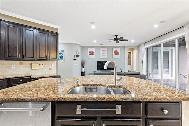 kitchen with light stone counters, a center island with sink, and sink