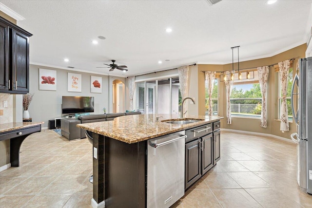 kitchen featuring stainless steel appliances, a kitchen island with sink, ceiling fan, ornamental molding, and sink