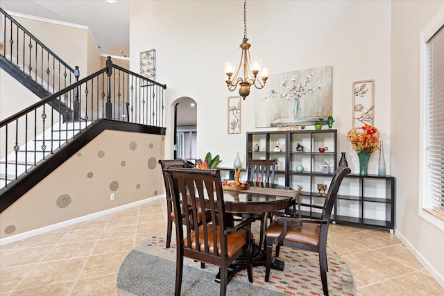 dining area with a towering ceiling, tile patterned floors, and an inviting chandelier