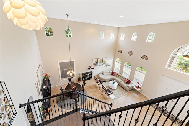 living room featuring a high ceiling, a notable chandelier, and a wealth of natural light