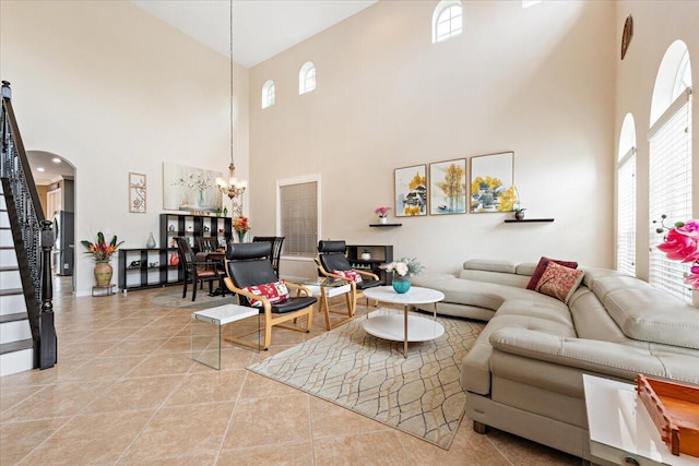 living room with a high ceiling, an inviting chandelier, and light tile patterned floors