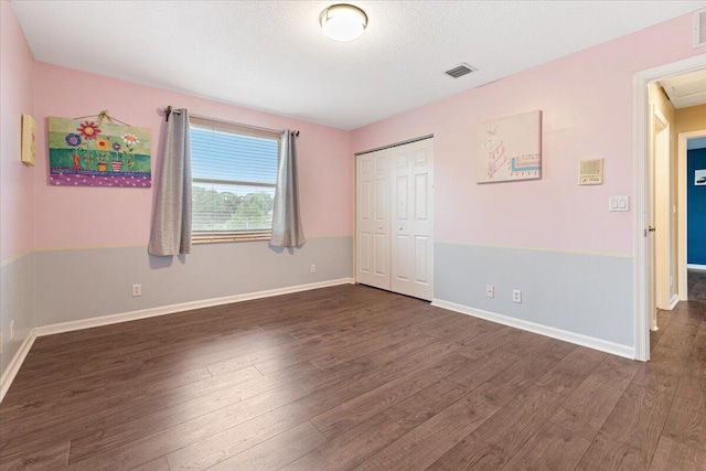 unfurnished bedroom featuring dark wood-type flooring and a closet