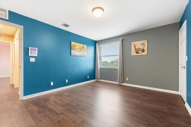 unfurnished room with a textured ceiling and dark wood-type flooring