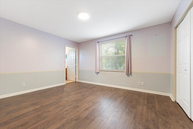 unfurnished bedroom with dark wood-type flooring and a closet