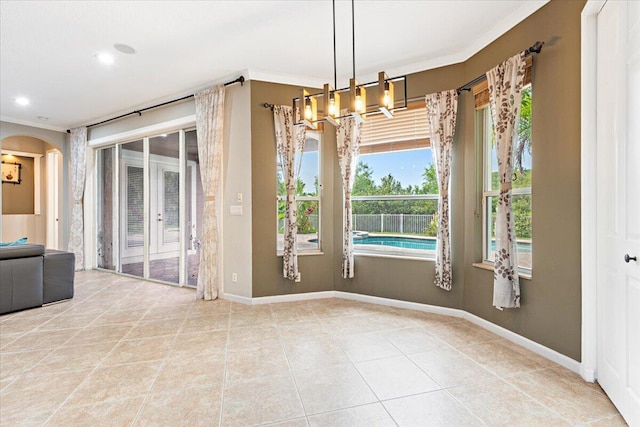 empty room featuring tile patterned floors, crown molding, and a chandelier