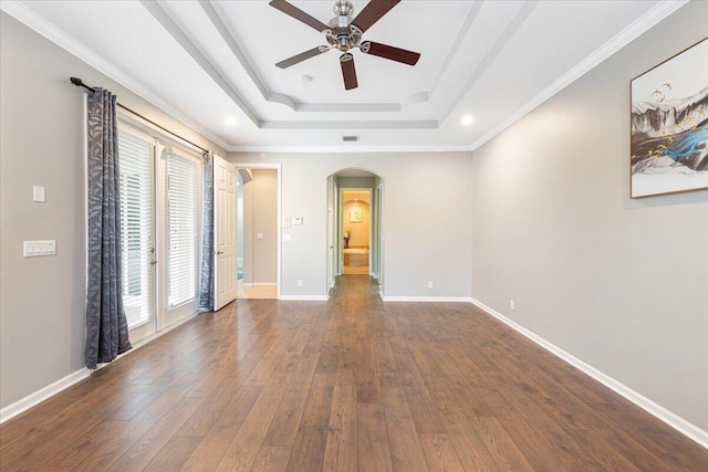 spare room featuring ceiling fan, dark wood-type flooring, plenty of natural light, and a tray ceiling