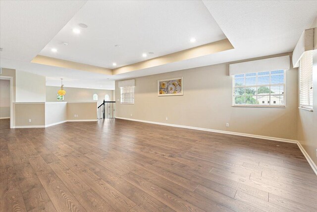 unfurnished living room featuring wood-type flooring and a tray ceiling