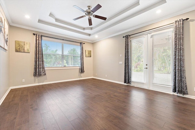 empty room with dark wood-type flooring, a raised ceiling, ceiling fan, and a wealth of natural light