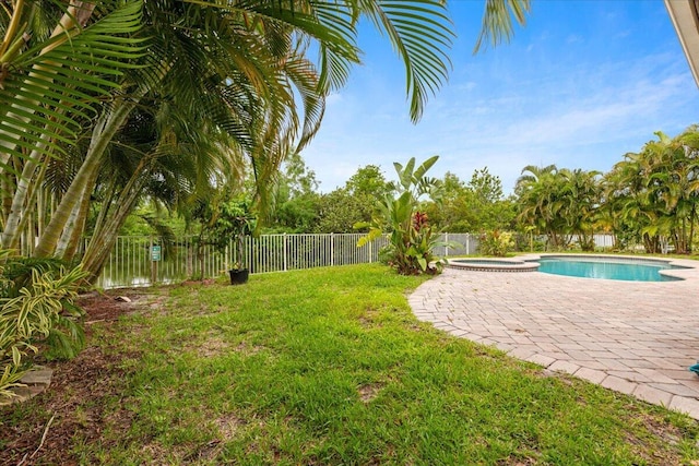 view of yard featuring a pool with hot tub, a patio area, and a water view