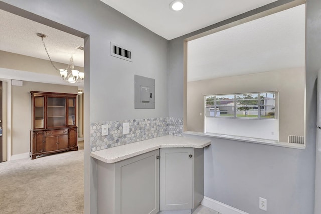 interior space featuring pendant lighting, light carpet, electric panel, and a chandelier