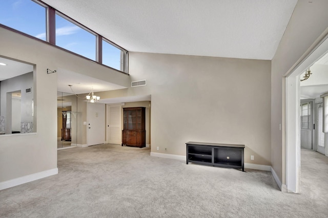 unfurnished living room featuring light carpet, high vaulted ceiling, and a notable chandelier