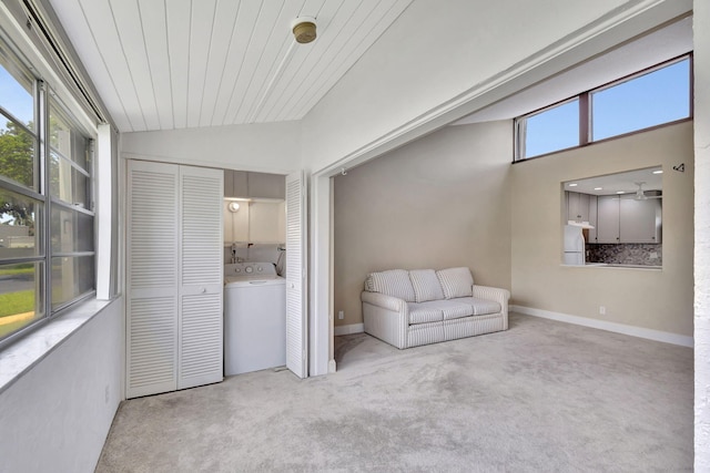 interior space featuring washer / clothes dryer, vaulted ceiling, plenty of natural light, and light colored carpet