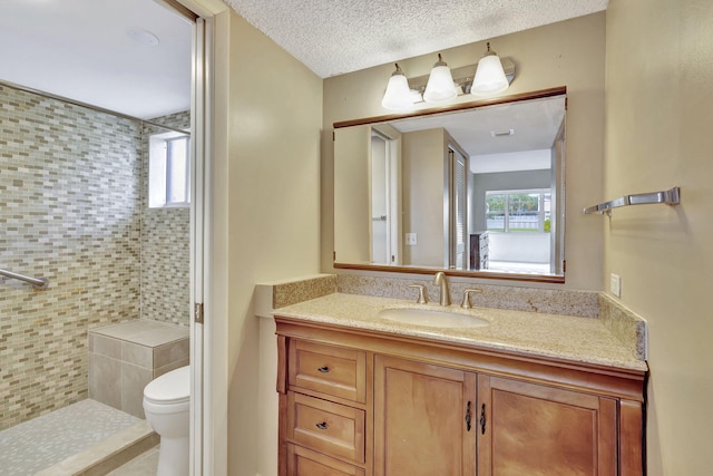 bathroom featuring a tile shower, vanity, and toilet