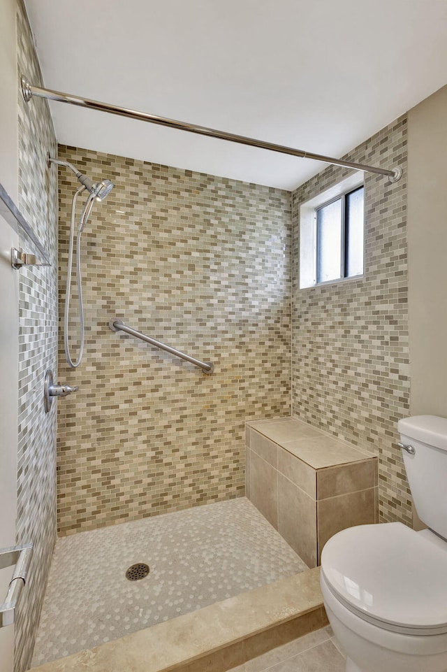 bathroom with tile patterned floors, toilet, and tiled shower