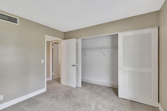 unfurnished bedroom with light carpet and a closet