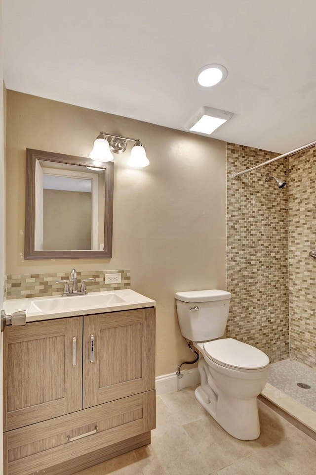 bathroom with a tile shower, vanity, and toilet