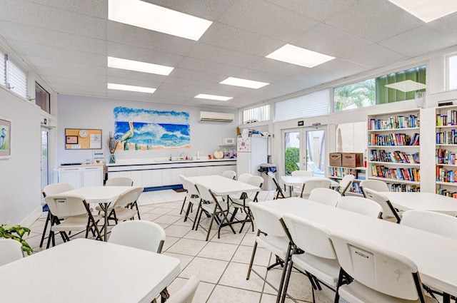 dining area featuring a wall mounted AC, a drop ceiling, and light tile patterned floors