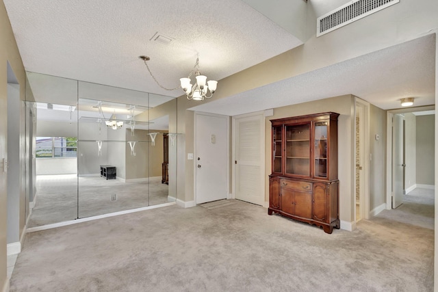 interior space featuring carpet, a textured ceiling, and a notable chandelier