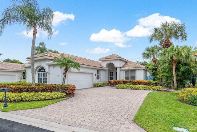 mediterranean / spanish-style house featuring a front yard and a garage