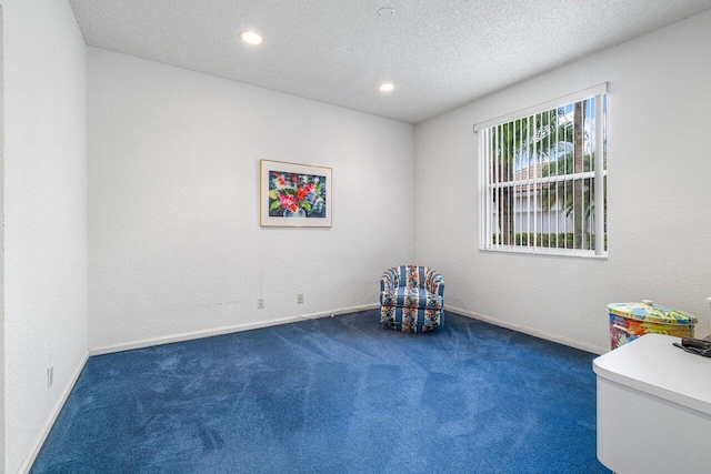 unfurnished room featuring a textured ceiling and dark colored carpet