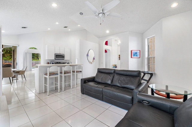 tiled living room featuring high vaulted ceiling, a textured ceiling, and ceiling fan